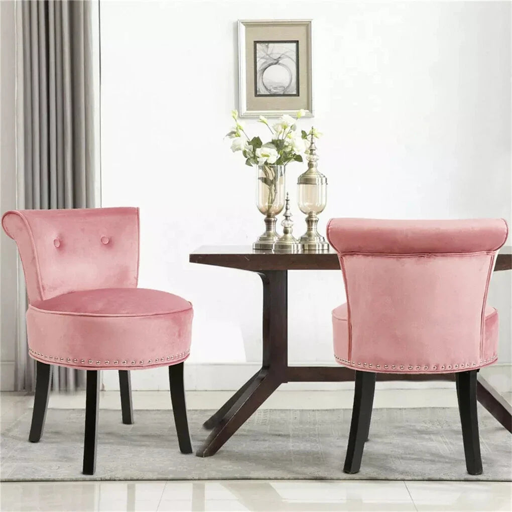 Two pink chairs in front of a wooden table with decorative items on a light-colored floor.