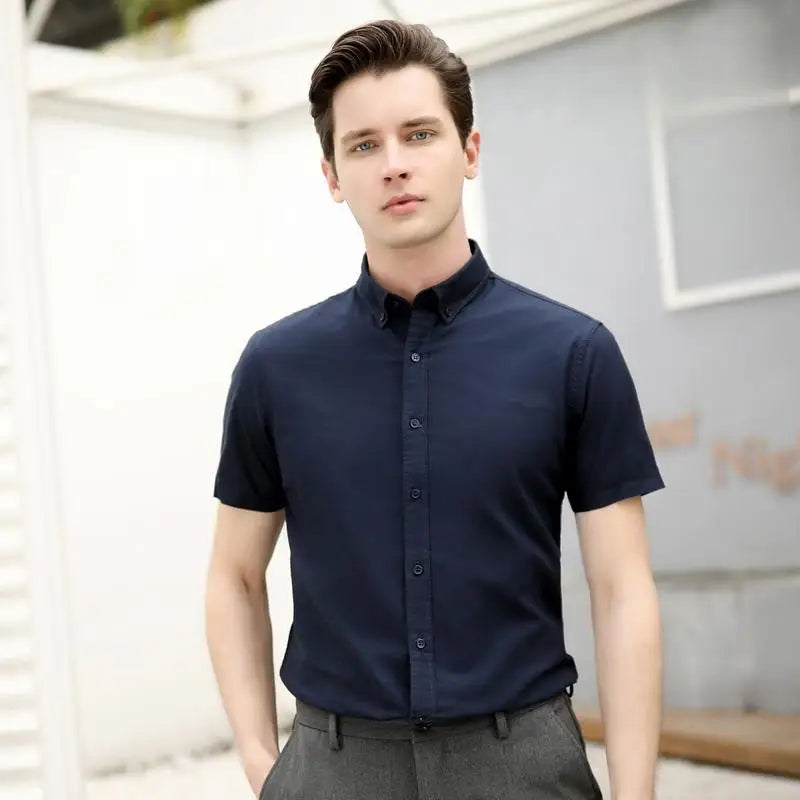 Man wearing a navy blue short-sleeve shirt against a neutral background