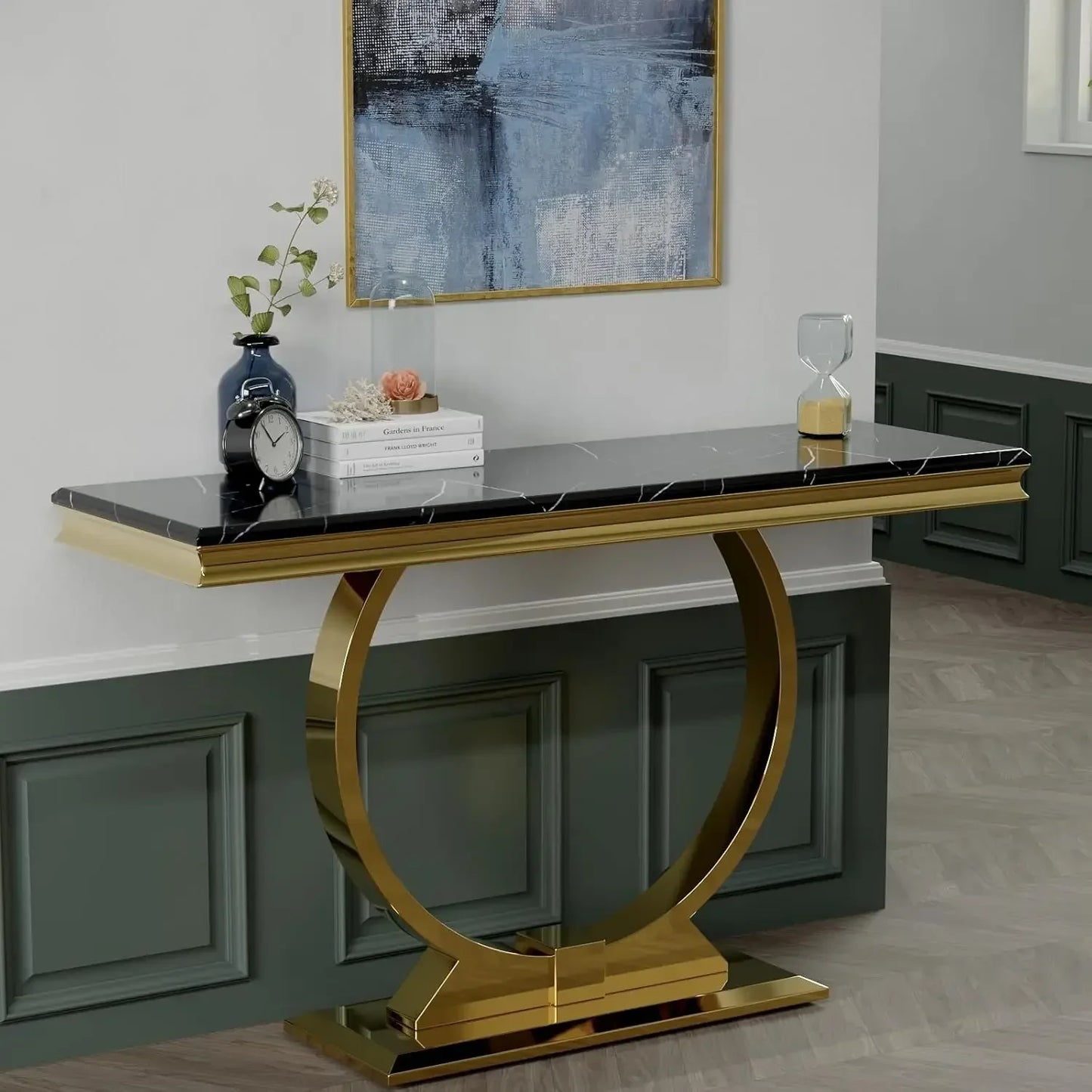 Console table with gold base and black marble top in a room with abstract art on the wall.