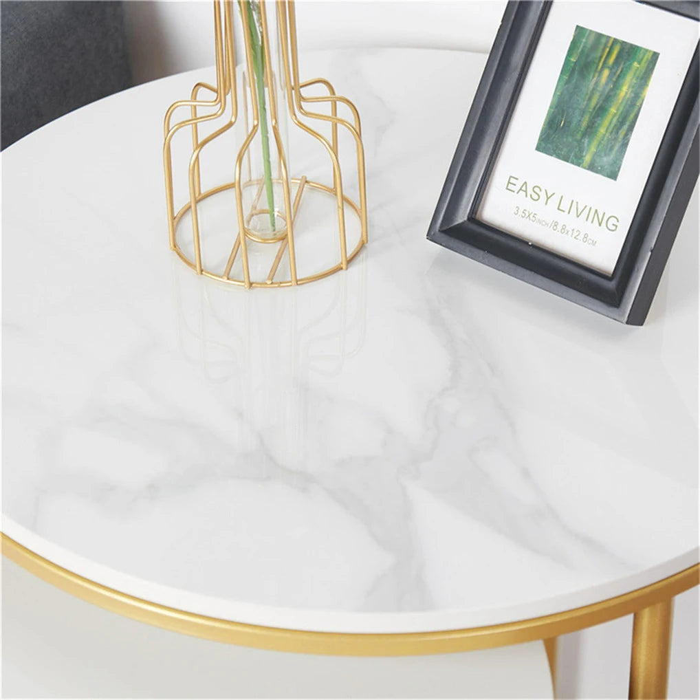 Round marble table with gold frame, decorative vase, and framed picture on a white surface.
