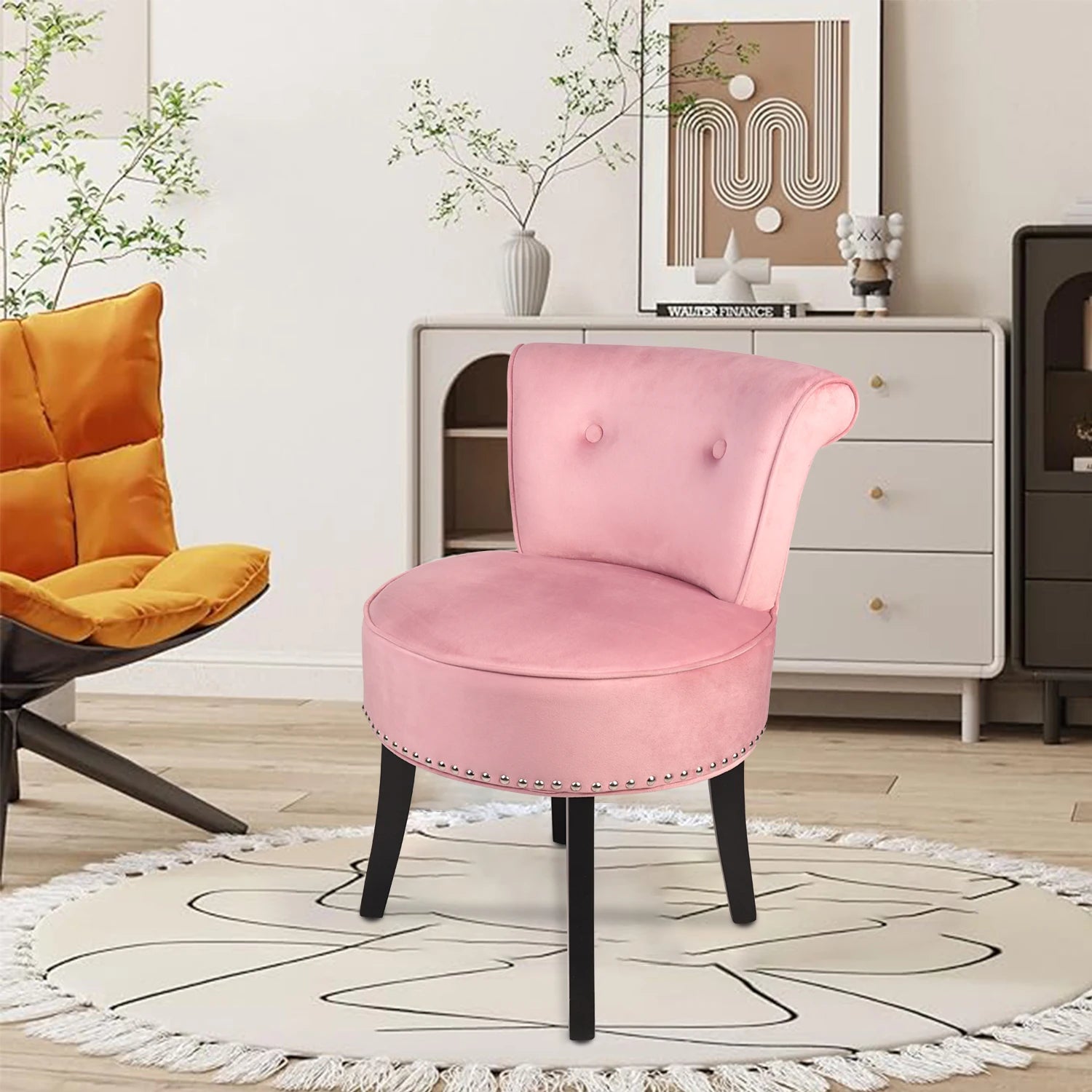 Pink chair in a room with a white dresser and decorative items.