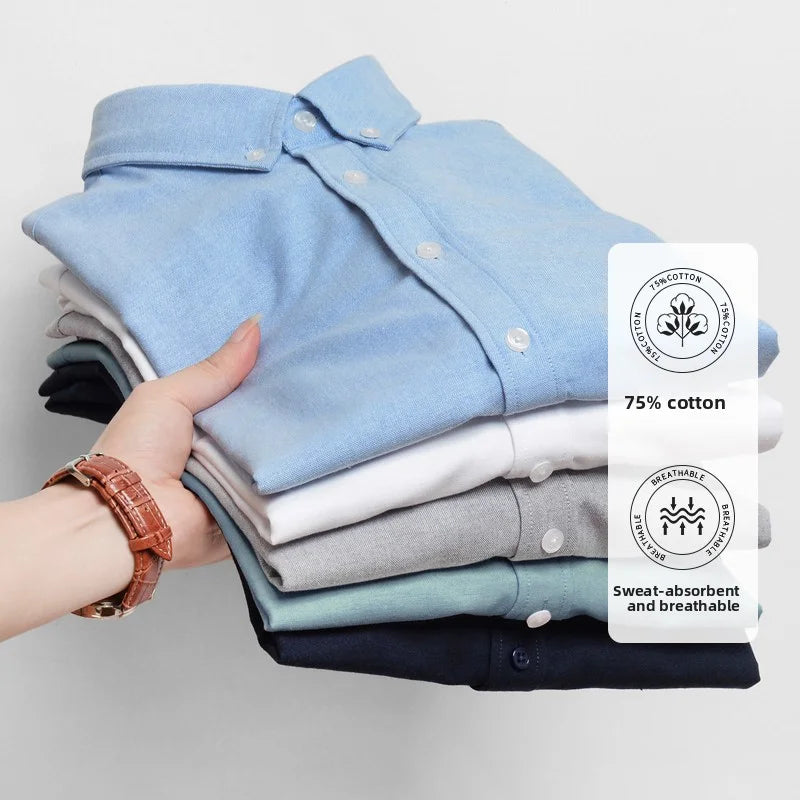 Stack of folded shirts held by a hand with a label on the right side, on a light gray background
