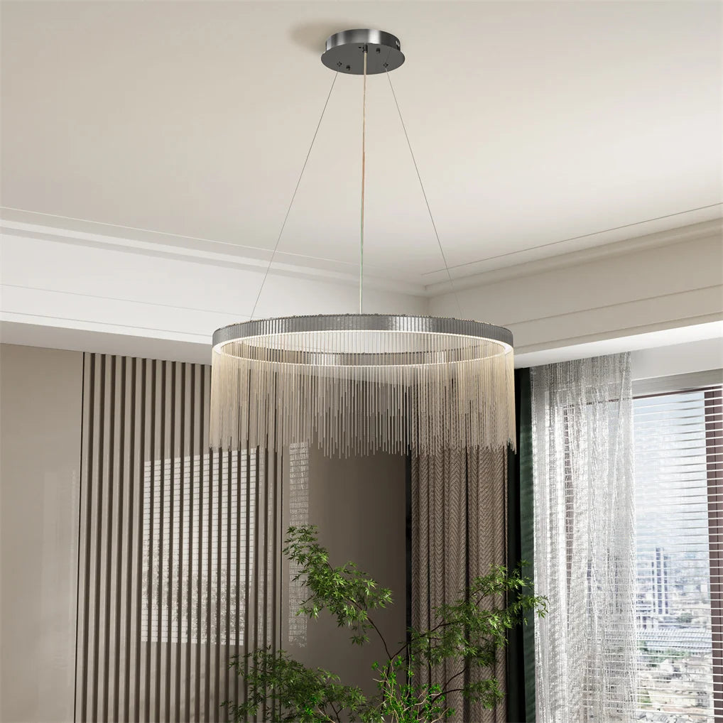 Modern chandelier hanging in a room with curtains and a plant.