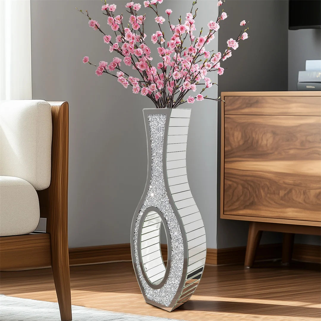 Decorative vase with pink flowers on a wooden floor in a room with furniture.