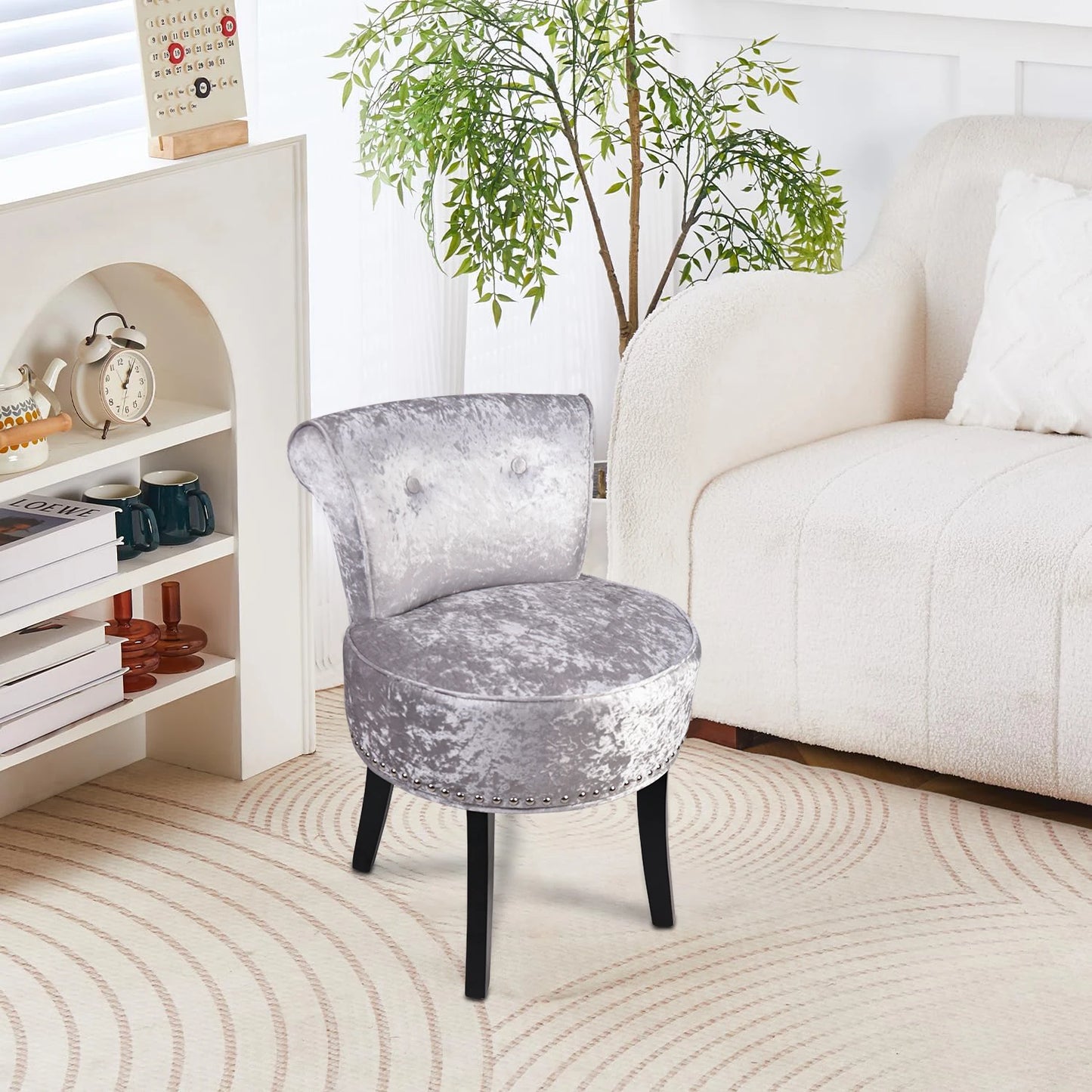 Gray velvet stool in a living room setting with a white sofa and bookshelf.