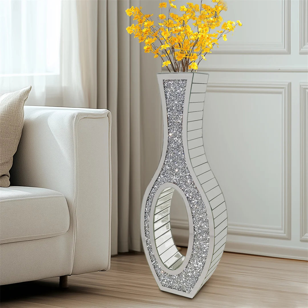 Decorative silver vase with yellow flowers on a wooden floor in a living room.