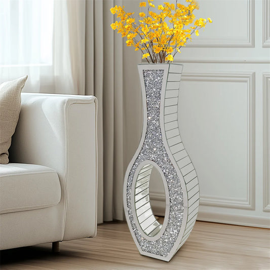 Decorative silver vase with yellow flowers on a wooden floor in a living room.