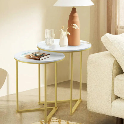 Set of round side tables with marble tops and gold frames in a living room setting.