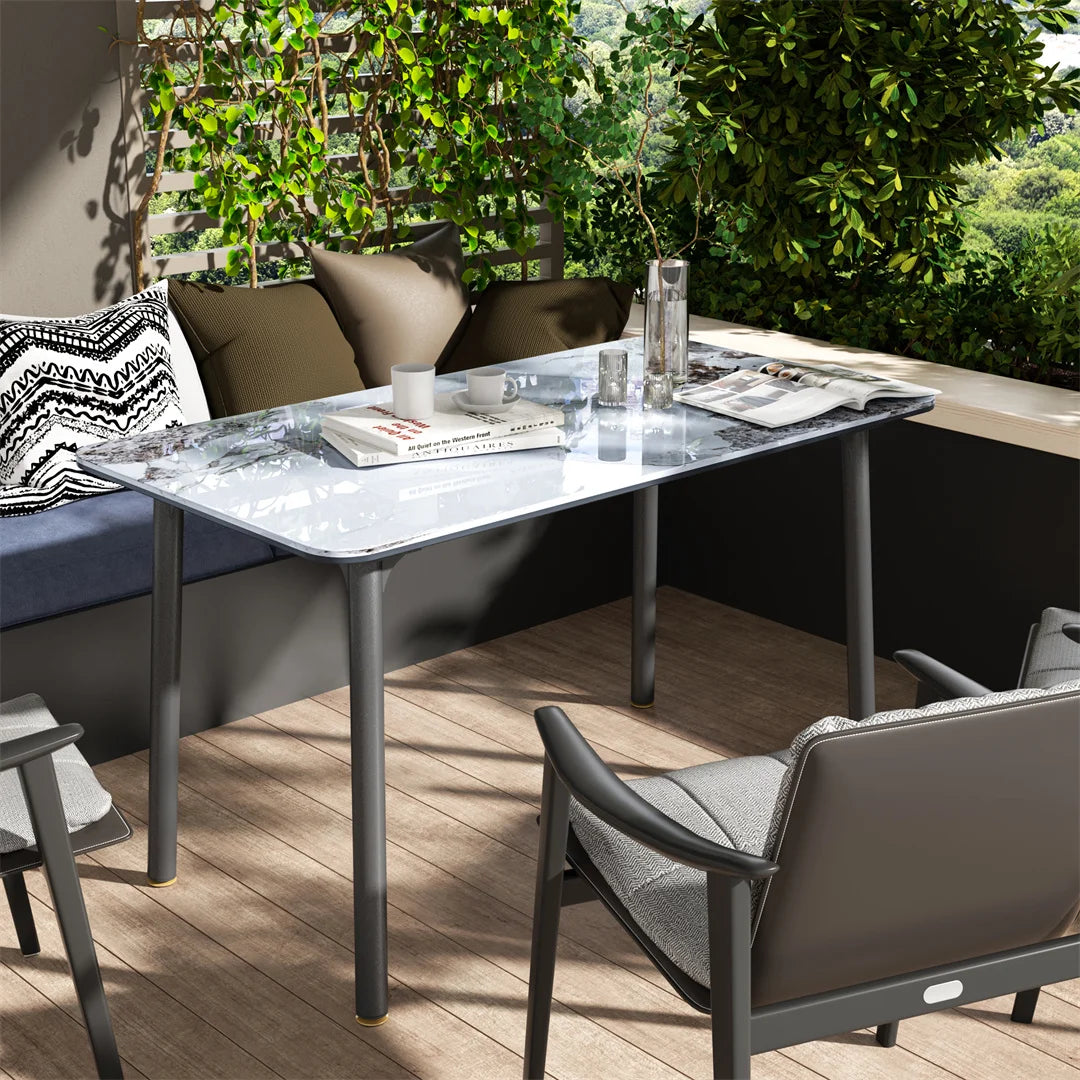Outdoor patio setting with a marble table, chairs, and cushions on a wooden deck.