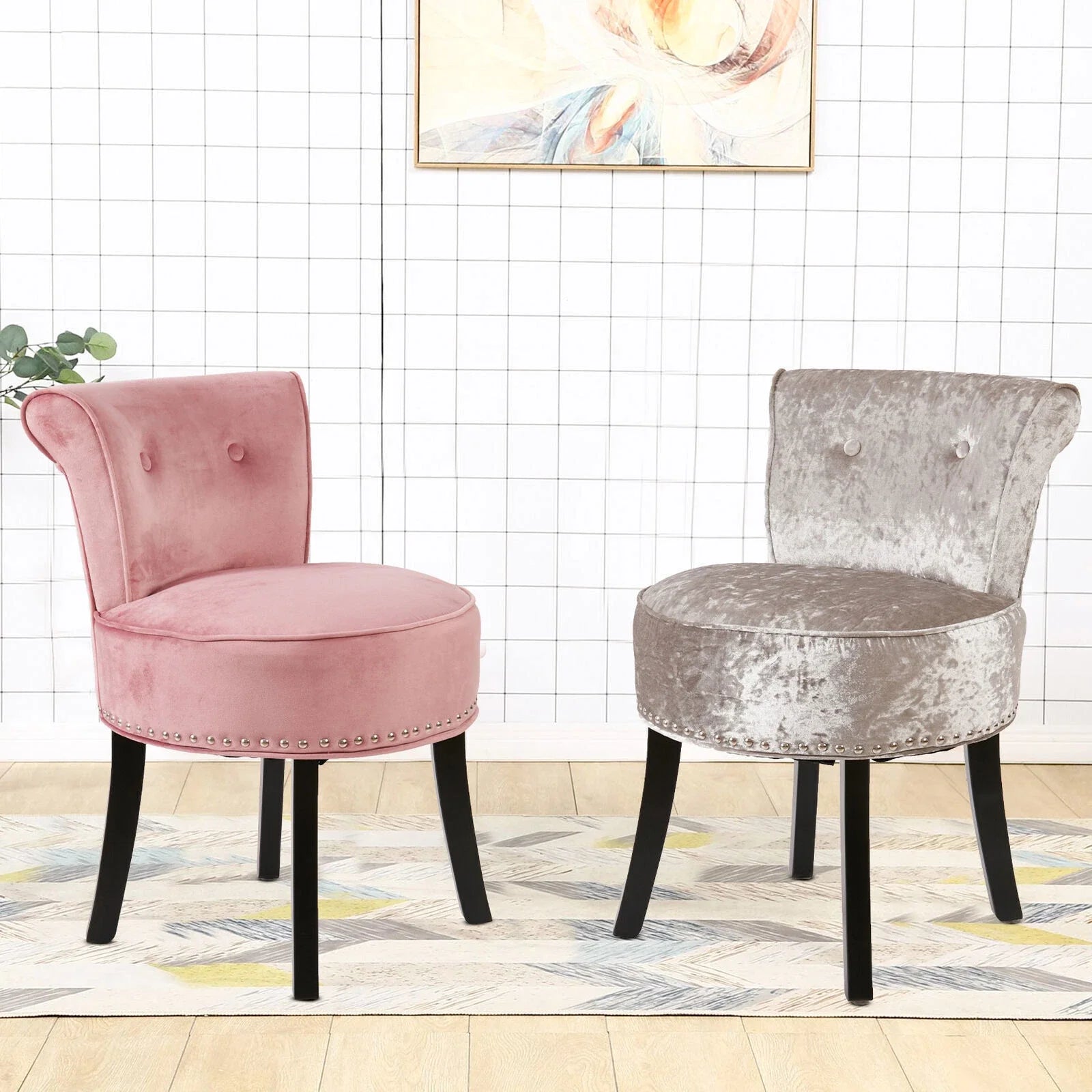 Two velvet chairs, one pink and one gray, on a patterned rug with a white grid wall in the background.