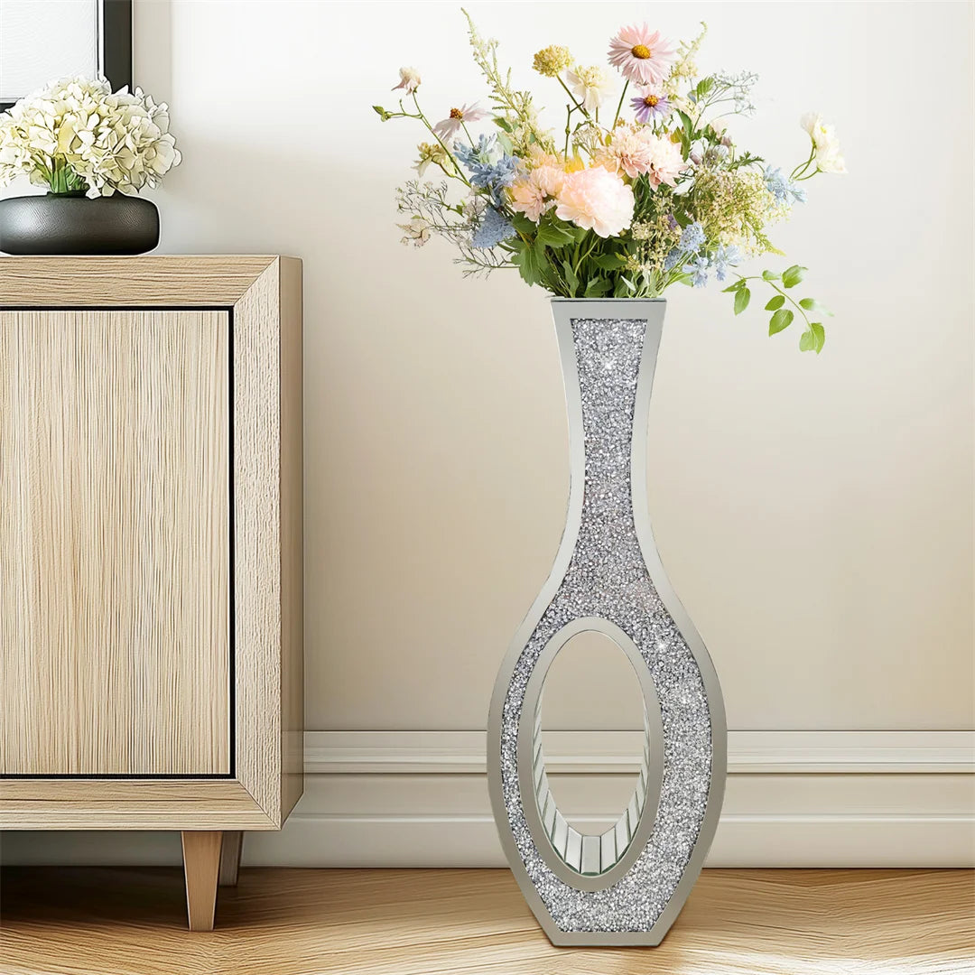 Decorative vase with floral arrangement on a wooden cabinet against a beige wall.