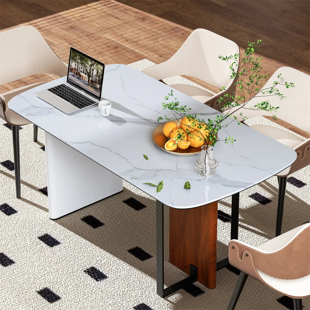Dining table with marble-like surface, laptop, and fruit bowl in a modern kitchen setting.